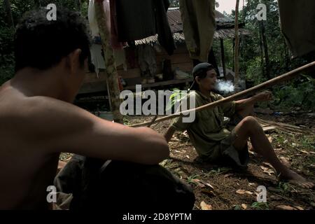 Tohab et Ramli Hutagalung, fermiers, ayant un repos à leur cabane de ferme dans une zone forestière, qui sur la limite ouest de l'écosystème de Batang Toru à Sitahuis, Central Tapanuli, Nord Sumatra, Indonésie. Les communautés vivant dans la forêt tropicale et autour de celle-ci dépendent en partie de la chasse alimentaire et de la collecte alimentaire en plus de l'agriculture. Les conservationnistes ont résolu ce problème en plaçant l'autonomisation des communautés comme partie intégrante de tout effort de conservation de la nature, en fournissant éducation et assistance aux communautés pour trouver une source de revenu alternative plus durable et plus écologique. Banque D'Images