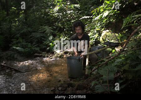 Un agriculteur qui prend de l'eau dans un petit ruisseau dans une forêt située à la limite ouest de l'écosystème de Batang Toru dans le district de Sitahuis, Central Tapanuli, North Sumatra, Indonésie. Banque D'Images