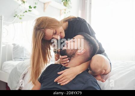 Un jeune couple marié s'embrasse dans la chambre à coucher pendant la journée Banque D'Images