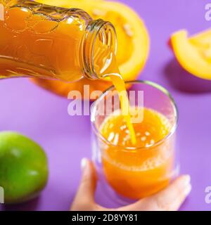 Fruit citrouille pomme carotte gingembre sur fond coloré mains jus savoureux Banque D'Images