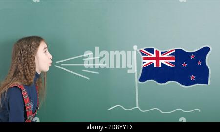 Une jeune fille qui soufflait sur le tableau scolaire est tirée sur le drapeau de la Nouvelle-Zélande. Photo haute résolution. Profondeur de champ complète. Banque D'Images