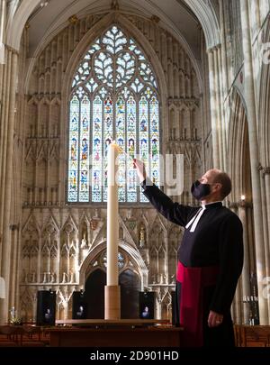 Le Revd Michael Smith, le pasteur Canon de York Minster, allume une bougie pendant la saison du souvenir de la Minster, qui se poursuit aujourd'hui avec une « journée pour se souvenir » spéciale de ceux qui sont morts en 2020. Banque D'Images