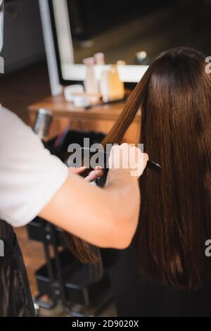 coiffeur peignant les cheveux de la femme sur un premier plan flou Banque D'Images