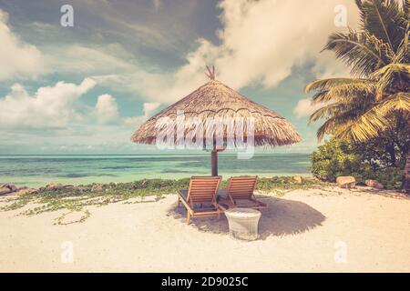 Fond de plage avec cocotier et lit de plage en bois sur sable avec belle mer bleue et ciel nuageux. Vintage été vacances paysage vacances vue Banque D'Images