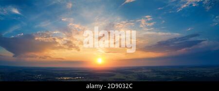 Paysage rural de printemps dans la soirée avec beau ciel brûlant, vue aérienne. Vue panoramique sur la forêt de pins, les champs et la rivière au coucher du soleil. Banque D'Images