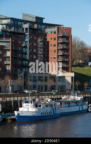 Tours en bateau devant les appartements sur la rive de la rivière Tyne, Newcastle upon Tyne, nord-est de l'Angleterre. Banque D'Images