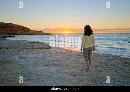 Femme sur la plage en admirant le coucher du soleil à Port Noarlunga, Australie méridionale Banque D'Images