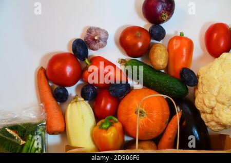 Légumes biologiques frais et colorés provenant du sac de shopping écologique en papier, capturés au-dessus de la vue du dessus, sur fond plat, sur fond blanc, livraison de nourriture Banque D'Images