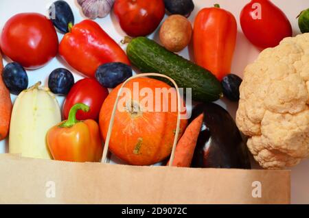 Légumes biologiques frais et colorés provenant du sac de shopping écologique en papier, capturés au-dessus de la vue du dessus, sur fond plat, sur fond blanc, livraison de nourriture Banque D'Images