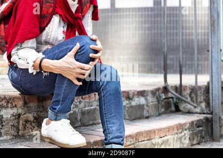 Femme assise dans la douleur avec les genoux sur les escaliers Banque D'Images
