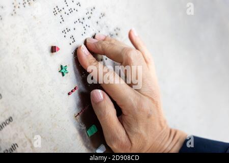 Lecture des doigts en braille tactile sur le panneau de messages du parc public Banque D'Images