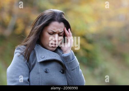 Une femme stressée se plaint de migraine à pied dans un parc hiver Banque D'Images