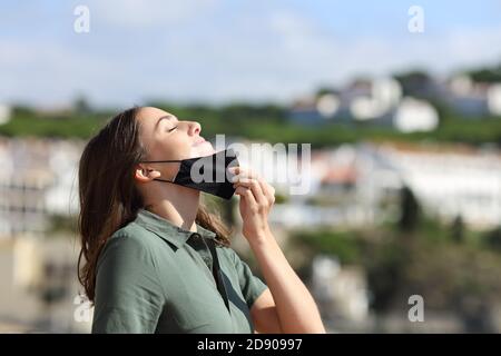 Femme détendue prenant le masque respirant de l'air frais dans un ville en vacances Banque D'Images