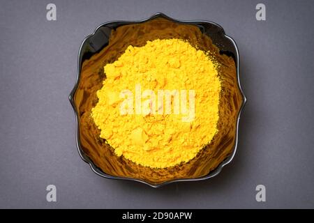 Vue de dessus gros plan de poudre de curcuma ou de curcuma dans un bol noir en céramique ou une assiette profonde sur fond sombre. Pose à plat Banque D'Images