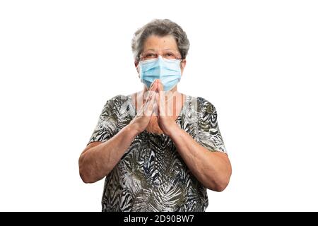 Vieille femme fidèle tenant les mains comme geste de prière portant le sras protection contre le virus covid masque chirurgical ou médical pour prévenir la contamination isolé sur Banque D'Images