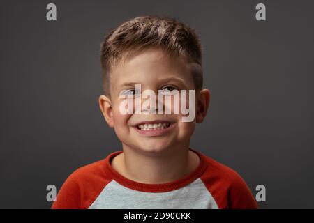 Joyeux petit garçon du Caucase, souriant. Petit enfant isolé sur fond gris Banque D'Images