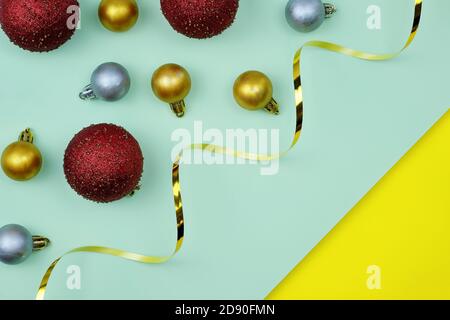 Boule à thème de Noël et ruban doré sur fond lumineux vue de dessus. Boules de Noël de différentes tailles en rouge, or et argent. Décorations pour le Banque D'Images