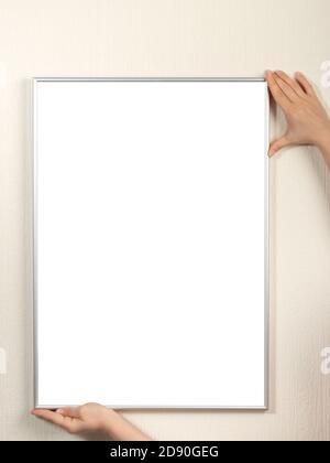 Certificat, diplôme, image, reconnaissance cadre blanc maquette. Femme accrochant une maquette de cadre photo sur un mur blanc. Banque D'Images