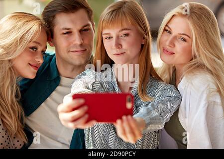 portrait d'un groupe heureux de jeunes amis caucasiens prenant des photos sur smartphone, souriant femmes et homme passent du temps ensemble dans le restaurant, réunis pour partager des nouvelles, concept d'amitié Banque D'Images