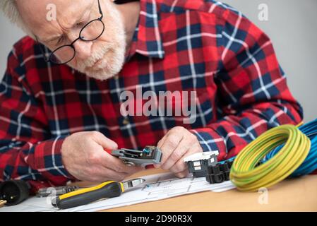 Un électricien principal dénude un fil Banque D'Images