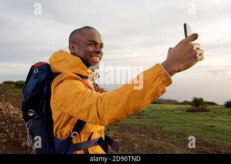 Portrait d'un jeune homme afro-américain souriant prenant le selfie à l'extérieur Banque D'Images