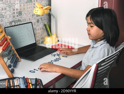 Une écolière asiatique étudie les mathématiques pendant son cours en ligne à la maison, zoom sur appel vidéo avec ordinateur portable à la maison. Nouveau coronavirus normal.Covid-19. Social Banque D'Images