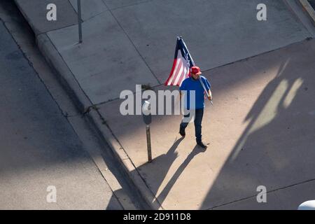 Austin, TX USA 30OCT20: Un partisan de Trump avec un drapeau américain et un drapeau du Texas modifié avec une feuille de marijuana à la place des défilés Lone Star tandis que d'autres bloquent un bus de campagne Biden-Harris au bureau AFL-CIO dans le centre-ville d'Austin. Le bus est arrivé à Austin à la suite d'un incident de circulation sur une autoroute bondée pendant qu'il voyageait de San Antonio. Les partisans de Biden à bord de l'autobus ont réclamé une douzaine de pick-up affiliés à Trump qui ont tenté de faire descendre l'autobus de la route. Plusieurs événements démocrates ont été annulés en raison de ces perturbations. Le FBI enquête sur l'incident. Banque D'Images