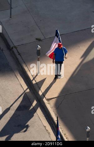 Austin, TX USA 30OCT20: Un partisan de Trump avec un drapeau américain et un drapeau du Texas modifié avec une feuille de marijuana à la place des défilés Lone Star tandis que d'autres bloquent un bus de campagne Biden-Harris au bureau AFL-CIO dans le centre-ville d'Austin. Le bus est arrivé à Austin à la suite d'un incident de circulation sur une autoroute bondée pendant qu'il voyageait de San Antonio. Les partisans de Biden à bord de l'autobus ont réclamé une douzaine de pick-up affiliés à Trump qui ont tenté de faire descendre l'autobus de la route. Plusieurs événements démocrates ont été annulés en raison de ces perturbations. Le FBI enquête sur l'incident. Banque D'Images