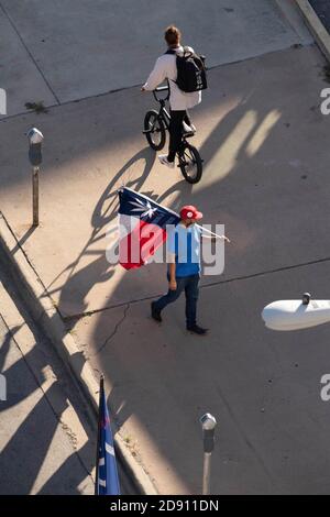 Austin, TX USA 30OCT20: Un partisan de Trump avec un drapeau américain et un drapeau du Texas modifié avec une feuille de marijuana à la place des défilés Lone Star tandis que d'autres bloquent un bus de campagne Biden-Harris au bureau AFL-CIO dans le centre-ville d'Austin. Le bus est arrivé à Austin à la suite d'un incident de circulation sur une autoroute bondée pendant qu'il voyageait de San Antonio. Les partisans de Biden à bord de l'autobus ont réclamé une douzaine de pick-up affiliés à Trump qui ont tenté de faire descendre l'autobus de la route. Plusieurs événements démocrates ont été annulés en raison de ces perturbations. Le FBI enquête sur l'incident. Banque D'Images