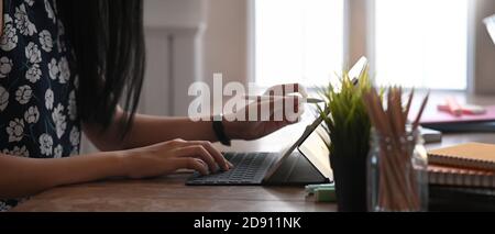 Coupe courte d'une jeune femme d'affaires attirante se concentre sur de nouveaux travaux sur une table en bois. Banque D'Images