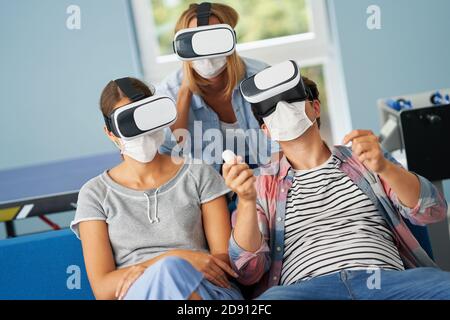Couple d'étudiants portant des masques jouant à des jeux vidéo dans le campus Banque D'Images