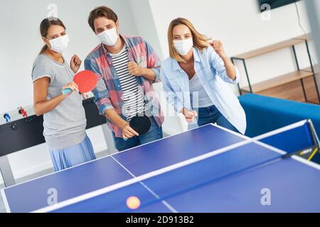 Groupe d'étudiants portant des masques jouant au tennis de table dans le campus Banque D'Images
