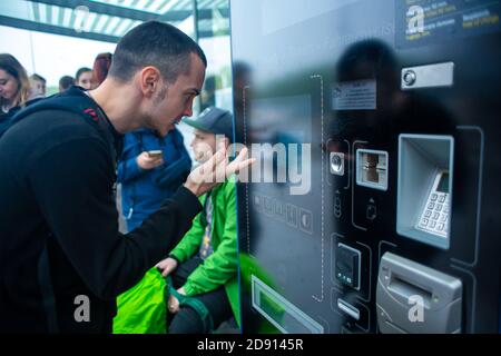 Un touriste achète un billet de bus pour la première fois à l'aide d'une machine à billets électroniques. Banque D'Images