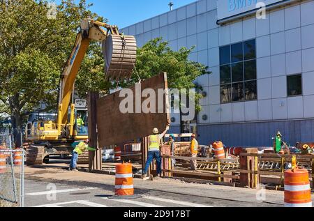 Les ouvriers installent l'étaiement de tranchée sur une excavation sur la deuxième avenue Dans Sunset Park Banque D'Images