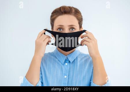 Jeune femme dans un masque médical et chemise bleue isolée sur fond blanc. Épidémie de grippe, allergie à la poussière, protection contre le virus. Pollution de l'air de la ville Banque D'Images