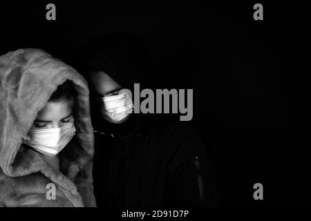 Jeune couple dans l'obscurité avec veste d'hiver avec masques médicaux de protection pour Covid-19, romantique et le concept de coronavirus Banque D'Images