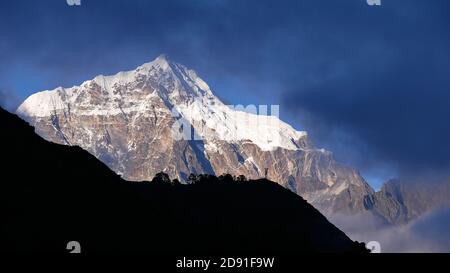 Vue imprenable sur la montagne majestueuse Taboche (pic 6 501 m) en regardant à travers les nuages avec silhouette de colline en premier plan depuis le point de vue du mont Everest. Banque D'Images