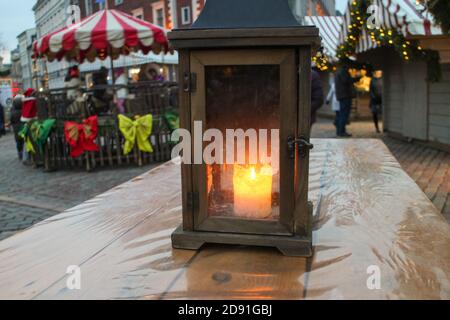 bougie allumée dans une lanterne en bois vintage sur toile de fond d'un marché de noël de la ville avec des décorations et éclairage de vacances Banque D'Images