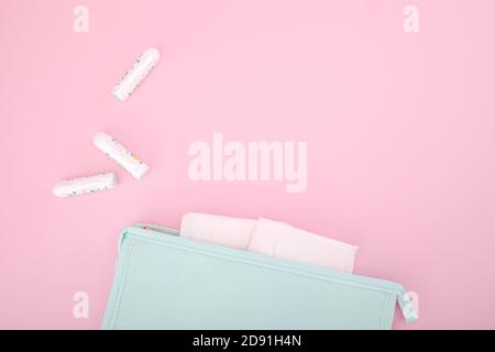 Tampons hygiéniques dans un sac cosmétique bleu et tampons un fond rose Banque D'Images