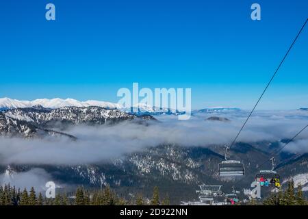 Station de ski slovaque à Jasna. Ciel bleu et brouillard léger entre les sommets de montagne. La neige brille au soleil. Télésiège Banque D'Images