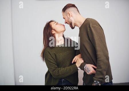 Un couple multiethnique heureux dans des vêtements décontractés est ensemble à l'intérieur dans le studio. Un homme de race blanche avec une petite amie asiatique Banque D'Images