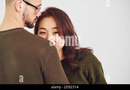 Un couple multiethnique heureux dans des vêtements décontractés est ensemble à l'intérieur dans le studio. Un homme de race blanche avec une petite amie asiatique Banque D'Images