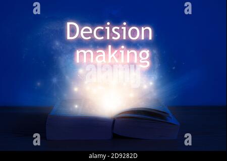 Livre ouvert avec inscription à la prise de décision. Lumière venant d'un livre ouvert avec prise de décision de mots. Banque D'Images