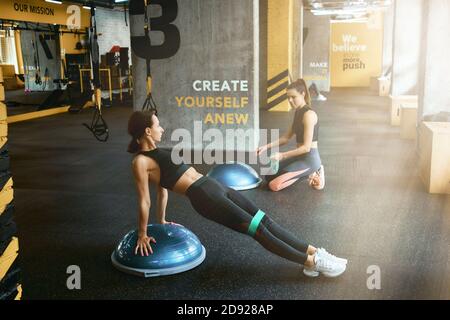 S'exercer ensemble. Deux jeunes femmes sportives en vêtements de sport s'entraîner au crossfit Gym, à l'aide d'un équipement de fitness spécial. Entraînement, entraînement, bien-être et soins du corps Banque D'Images