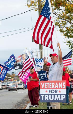 Un homme sur le trottoir local fait un rallye sur le drapeau et affiche un Quatre signaux de main fingered - symbolisant son soutien à Trump séjour au bureau pour quatre personnes de plus Banque D'Images