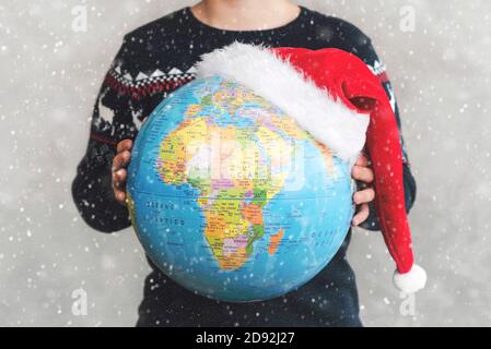 Joyeux Noël. enfant tenant un globe terrestre avec un chapeau de père Noël avec des flocons de neige Banque D'Images