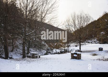 Aire de pique-nique enneigée au milieu de la montagne entourée par les arbres Banque D'Images