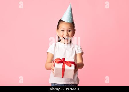 Bonne fille asiatique vous donnant boîte cadeau au studio jaune Banque D'Images