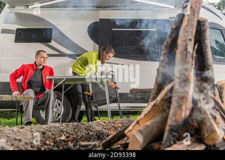 Couple caucasien se divertir devant un feu de camp pendant leur voyage de camping-car en voiture de fin de semaine. Terrain de camping. Banque D'Images