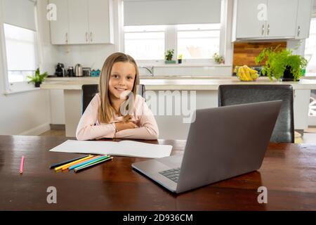 Bonne écolière sur ordinateur portable regardant la leçon en ligne apprendre à distance à la maison dans l'isolement. L'éducation, les quarantaines et les écoles rouvrant ou shuttin Banque D'Images